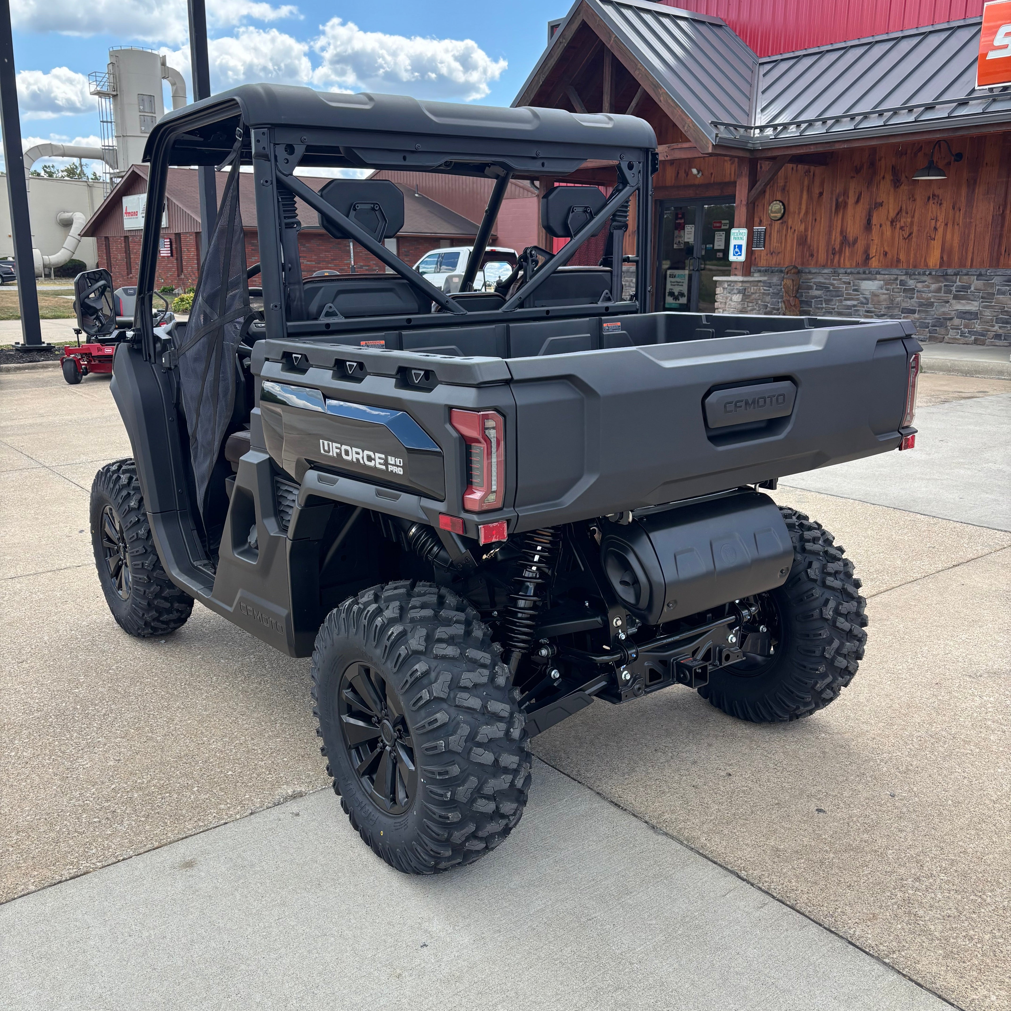 Black off-road vehicle on a sidewalk with a building and blue sky in the background