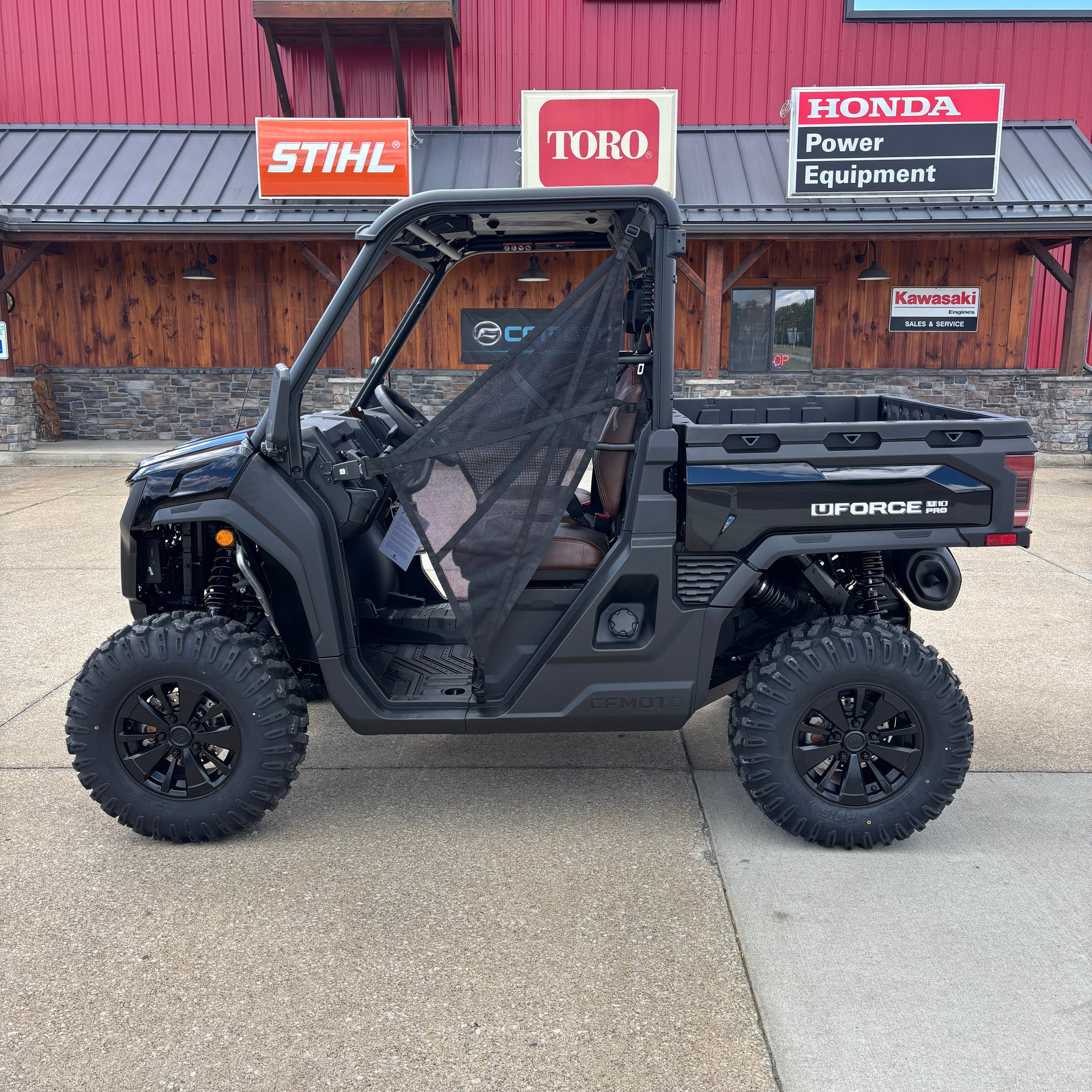 Black off-road vehicle parked in front of a red building with various signs.